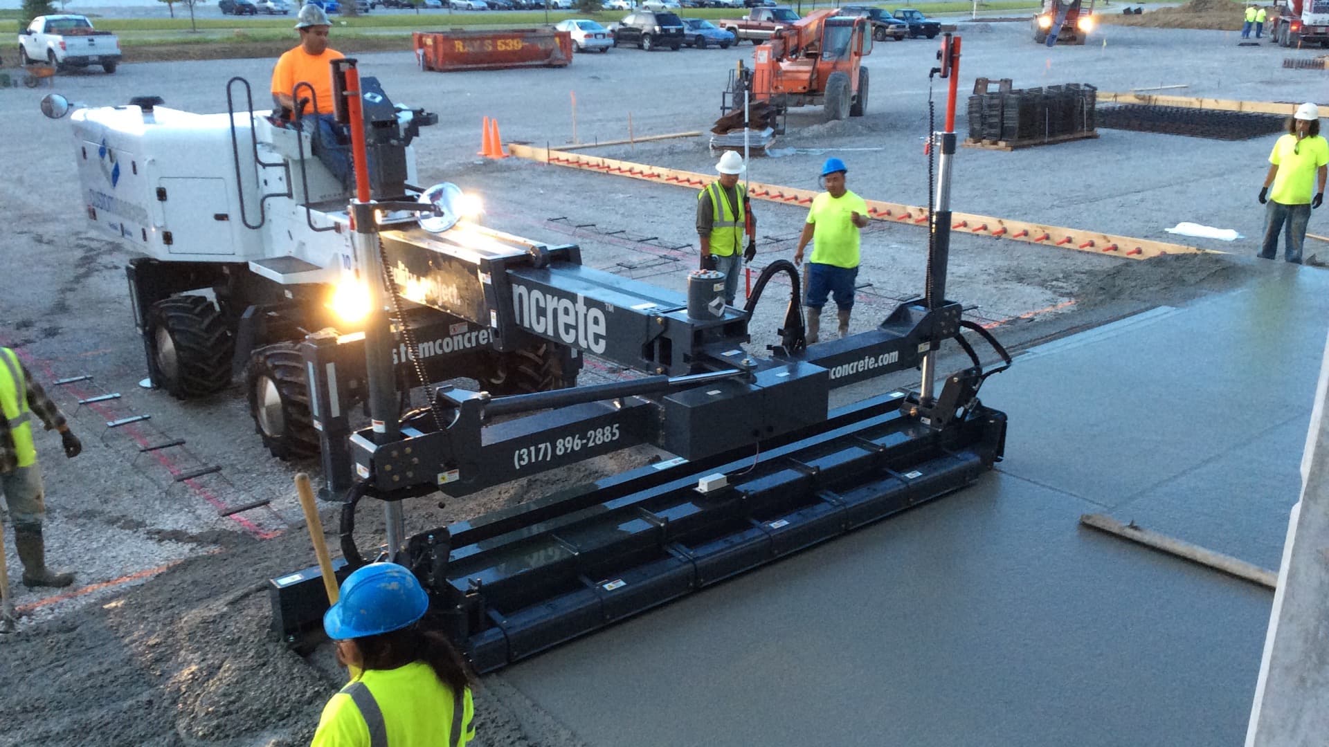Ride-on laser screed leveling a freshly placed commercial concrete slab